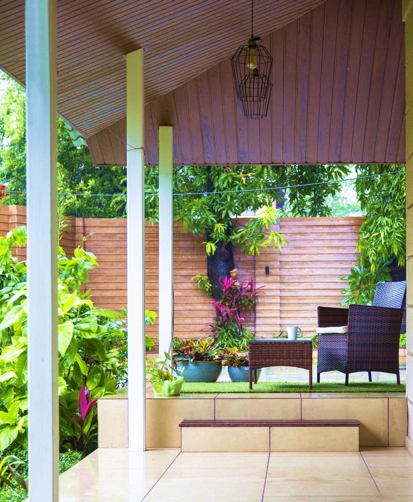 Farmhouse patio with wood-beam ceiling, timber columns and surrounding greenery, Badalapur