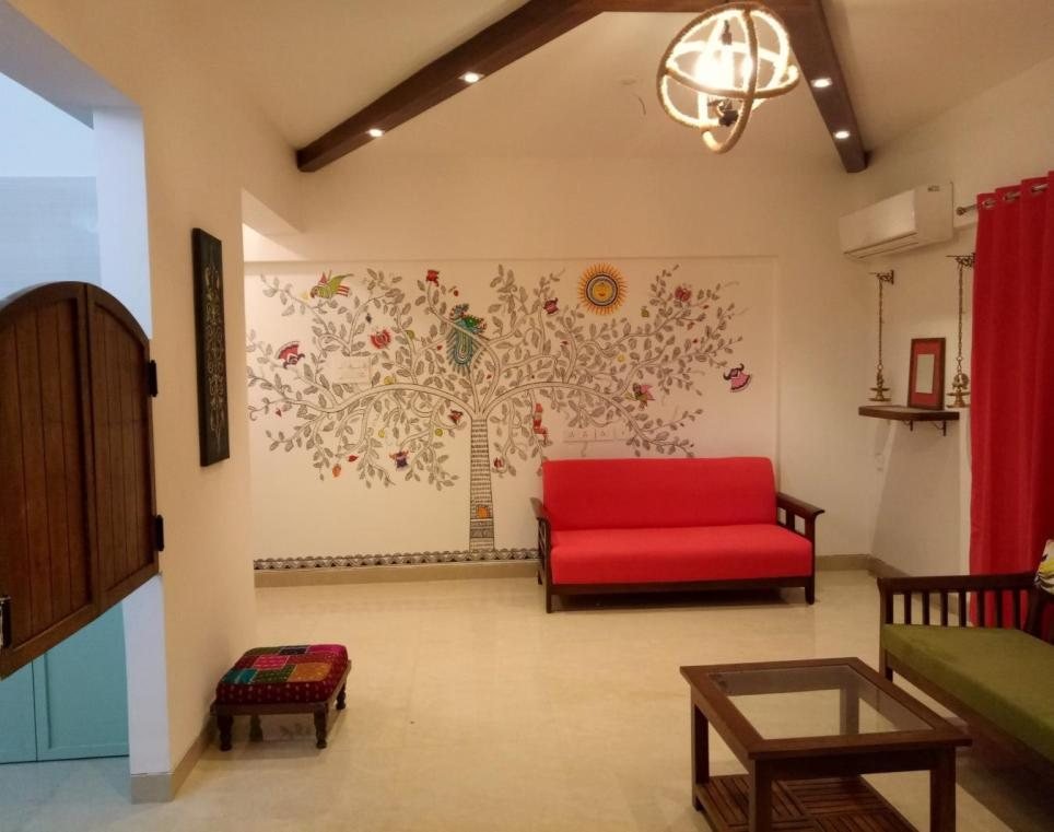 Weekend home living room in Goa with a red accent chair and carved wooden doors